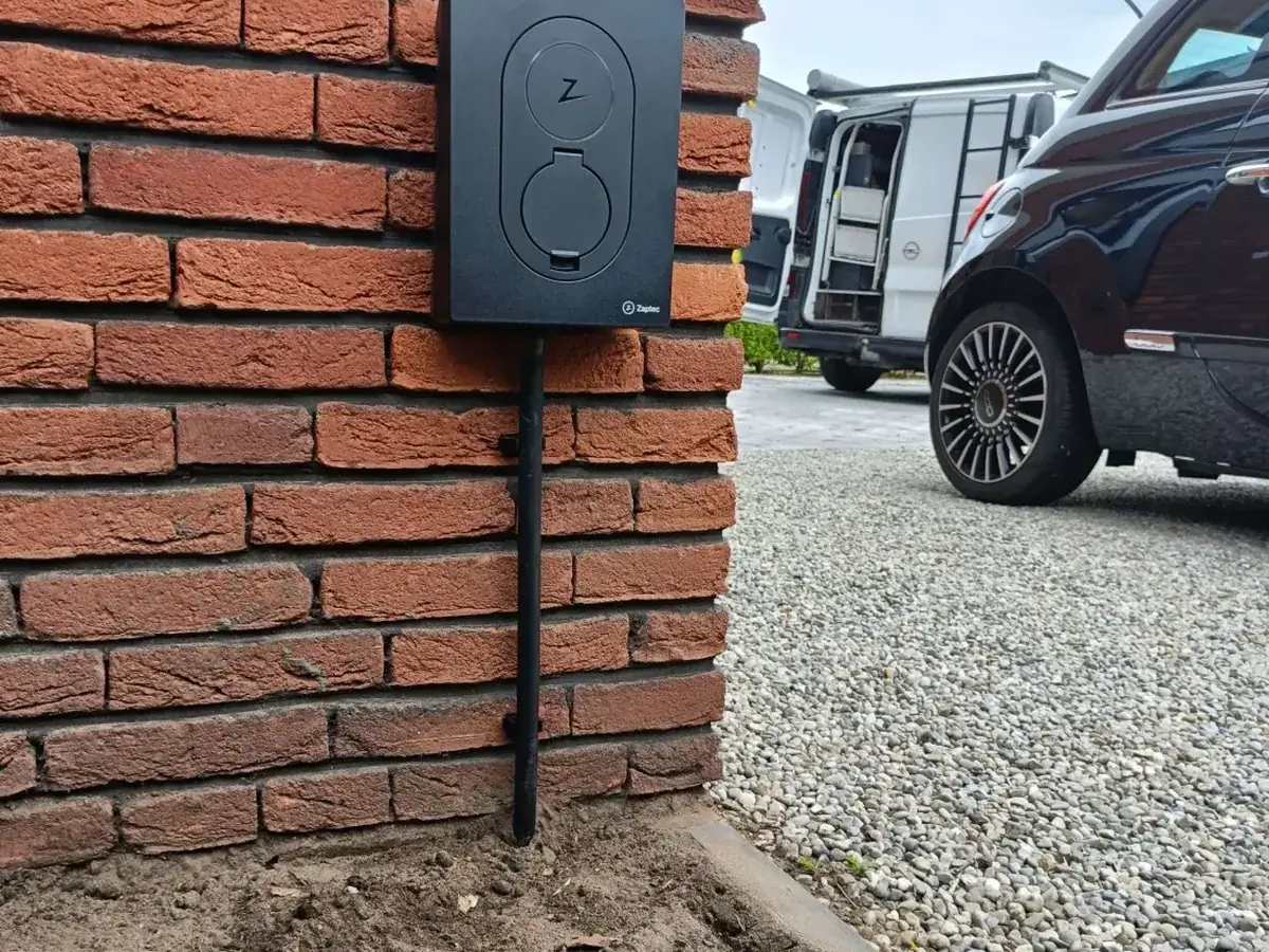 Zaptec Go laadpaal gemonteerd op een gevel naast een elektrische auto